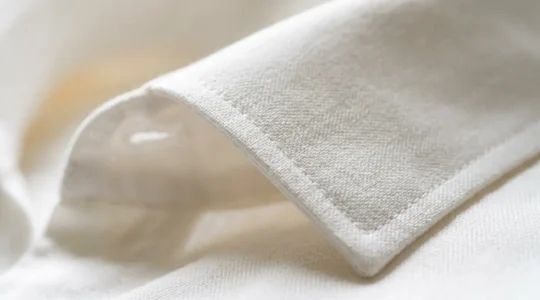 Dettaglio ravvicinato di un colletto di camicia bianca perfettamente pulito e stirato su sfondo minimalista