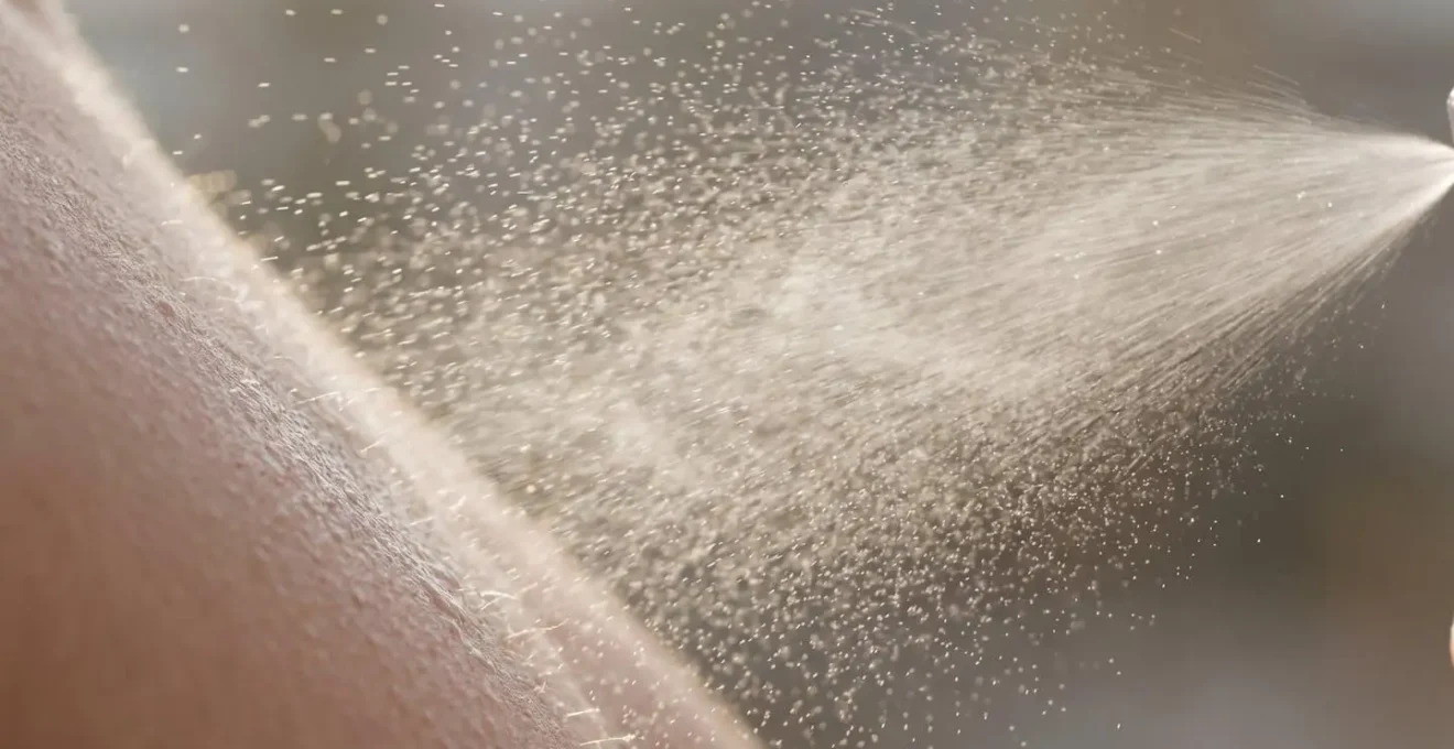 Primo piano di vaporizzazione spray protettivo trasparente su viso truccato